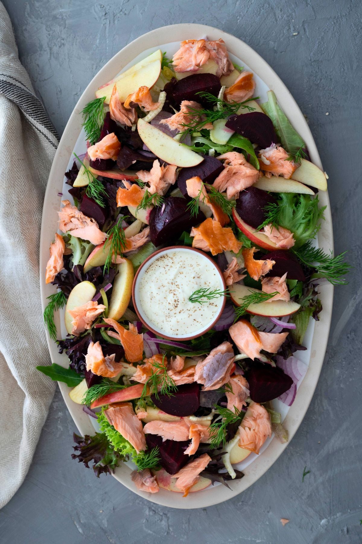 hot smoked salmon salad on a large platter. A small bowl of horseradish dressing is in the middle of the salad.