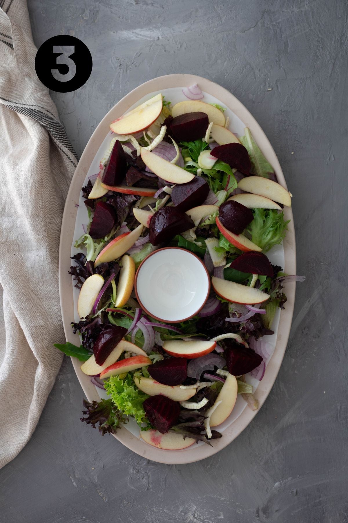 Beetroot and apple slices on a large platter. A small empty bowl sits in the middle of the platter.