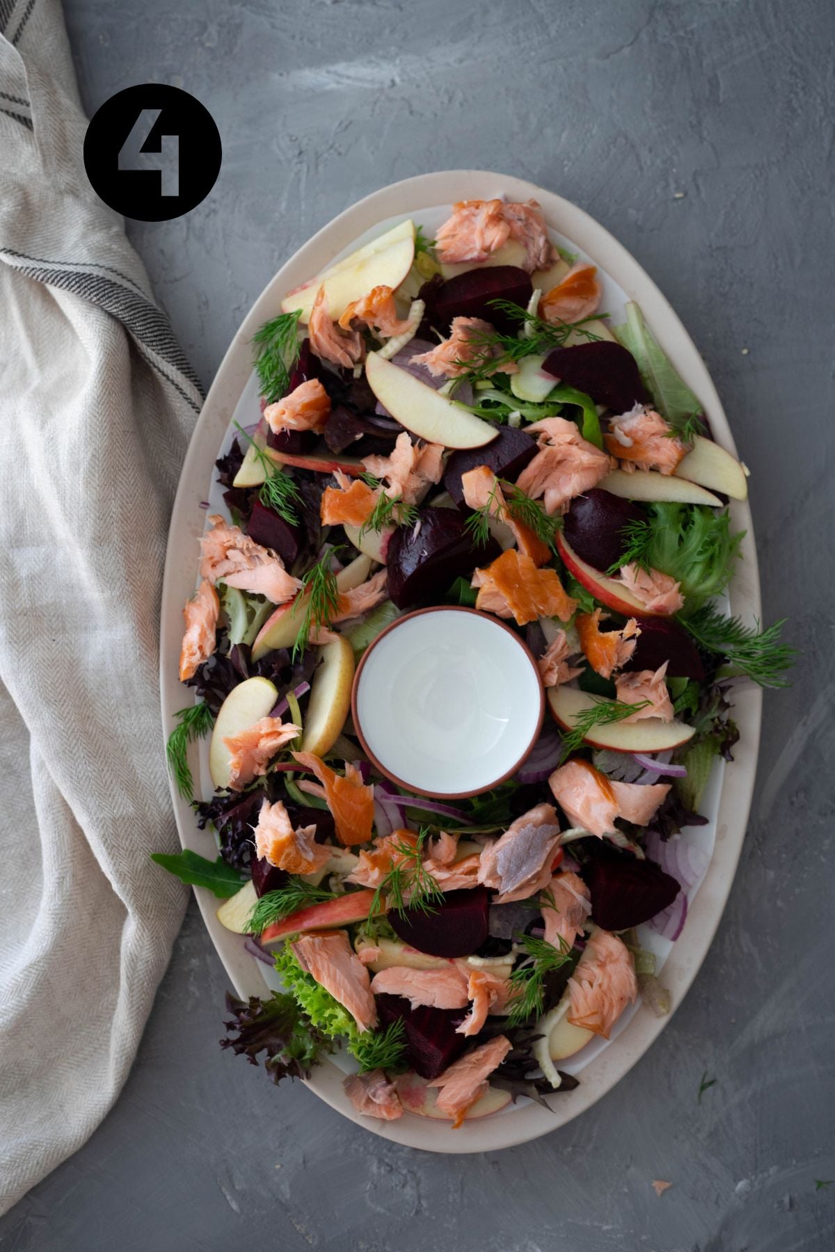 hot smoked salmon topped onto remaining salad ingredients. A small, empty bowl sits in the middle of the platter.