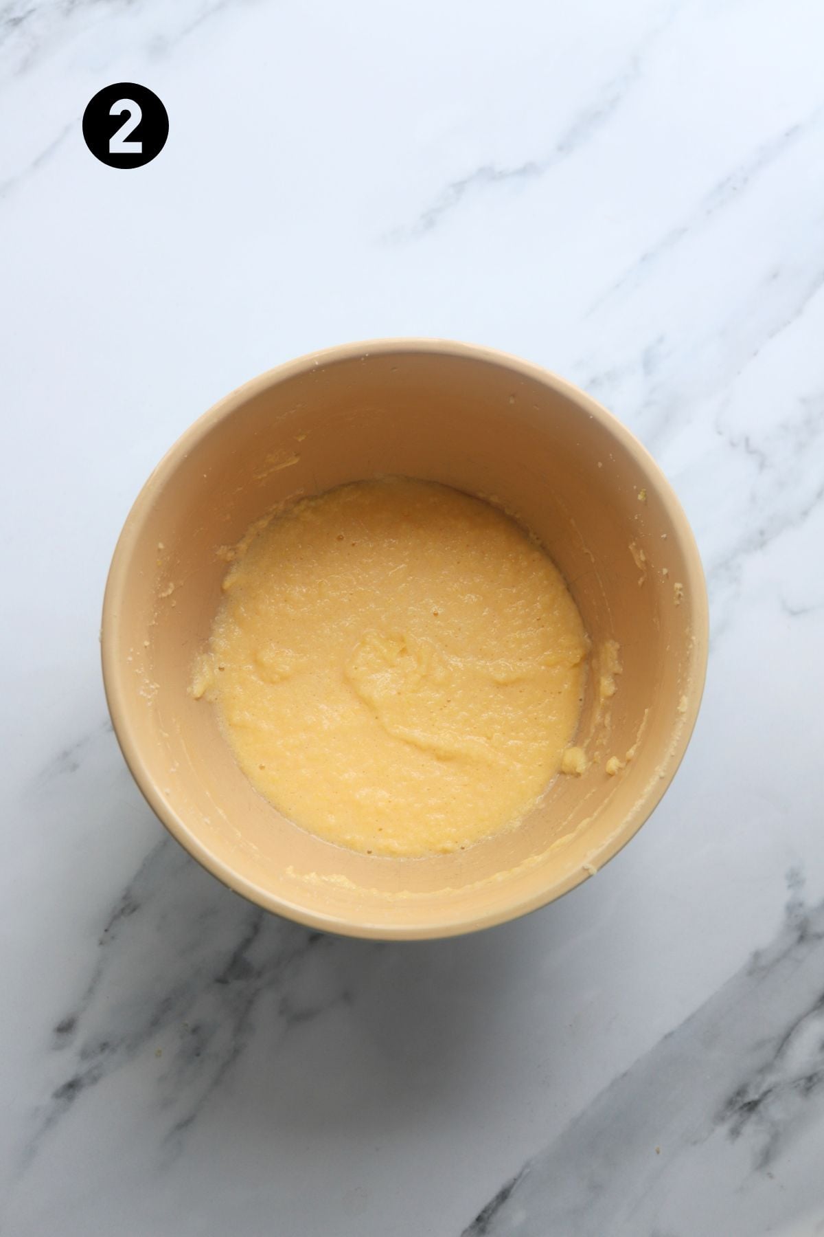 eggs added to butter, sugar and zest in a large bowl on a marble board.