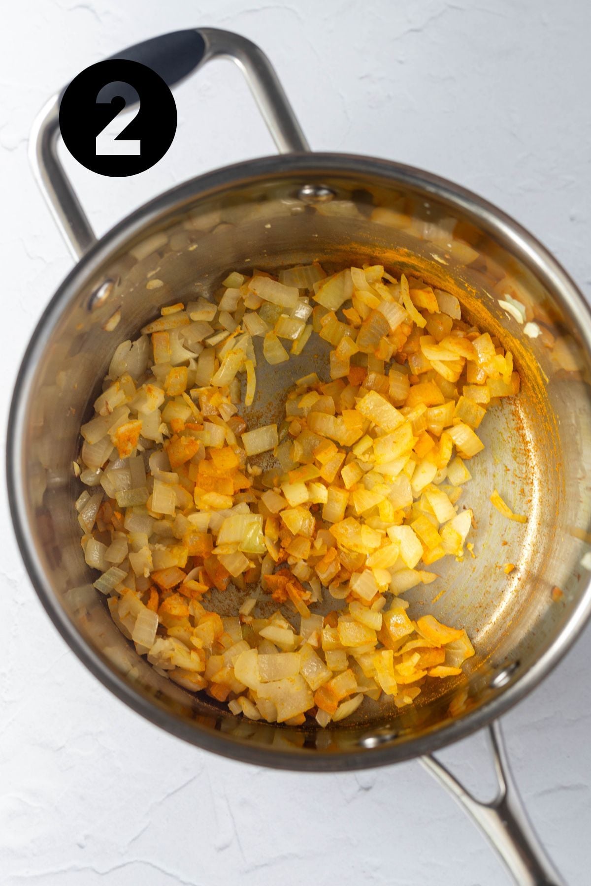 Tumeric added to garlic and onion mix in saucepan.
