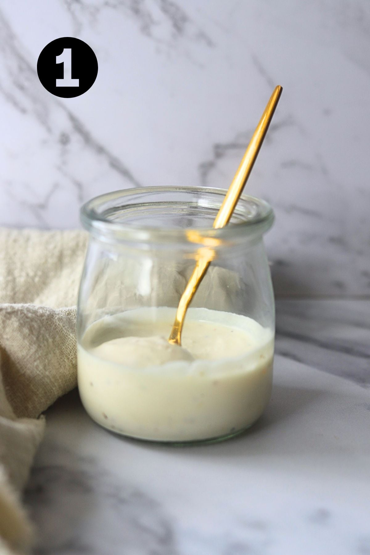 small jar of horseradish dressing with a gold spoon in the jar.