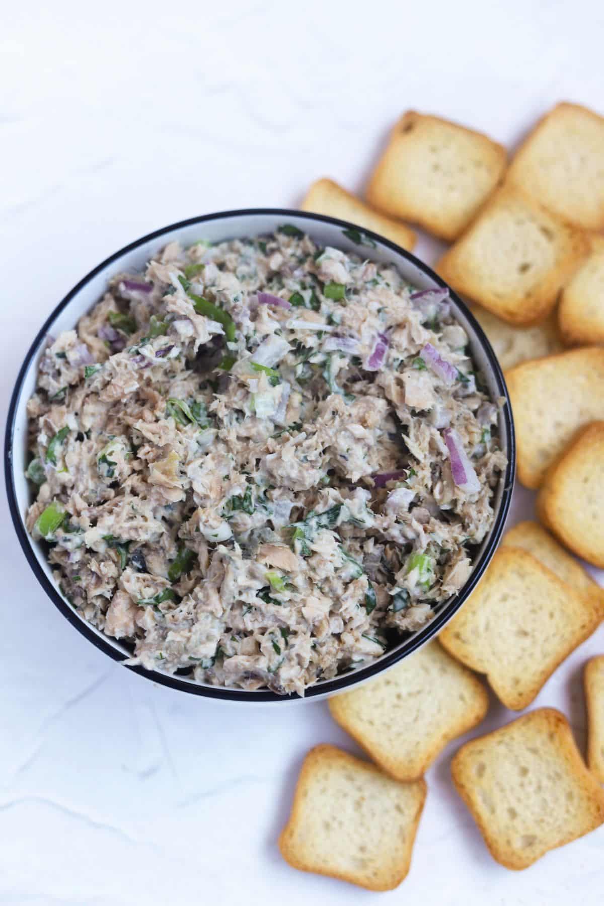salmon dip on board surrounded by mini toasts.
